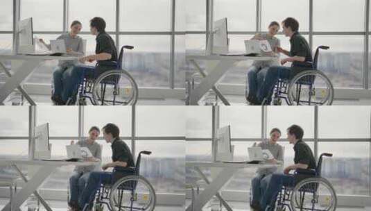 同事女人向坐轮椅的男人展示财务图文件在上高清在线视频素材下载