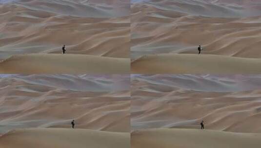 航拍男人行走在新疆库木塔格沙漠中高清在线视频素材下载