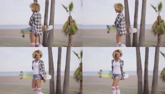 海滩上拿着滑板的年轻女子高清在线视频素材下载
