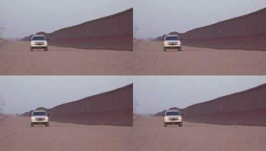 在边境墙旁边道路上行驶的边境巡逻车高清在线视频素材下载