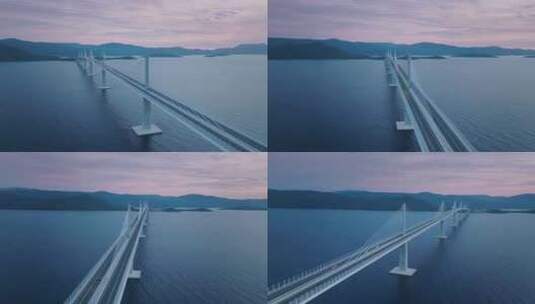 粉红色日落时横跨蓝色大海的雄伟桥梁。高清在线视频素材下载