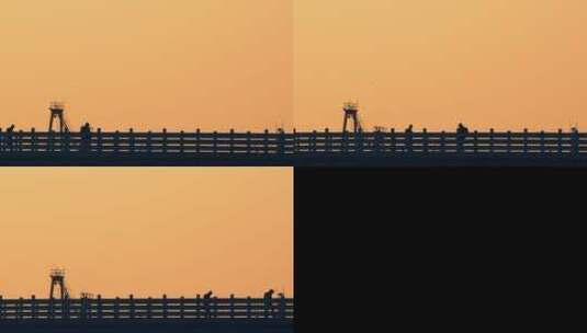 剪影夕阳日落桥边栏杆栅栏路人行走路过建筑高清在线视频素材下载