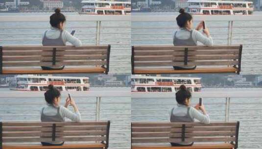 一位美女坐在海边公园椅子上拿手机拍照高清在线视频素材下载