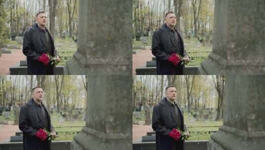 男人手捧鲜花站在墓碑前高清在线视频素材下载