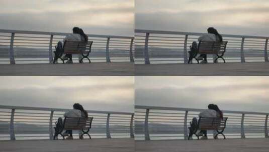 一对情侣坐在海边公园的椅子上谈情说爱高清在线视频素材下载