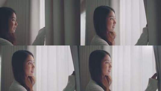 快乐的年轻亚洲女人在家里慢动作打开窗帘的高清在线视频素材下载