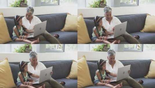 出生的祖母和孙女坐在沙发上，与笔记本电脑高清在线视频素材下载