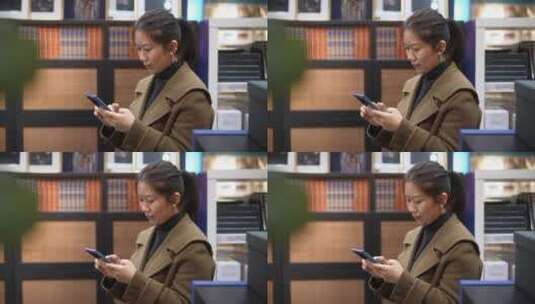 中年女性在书店书架前使用手机高清在线视频素材下载