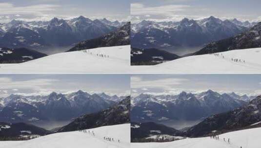 冬季鸟瞰一群穿着雪鞋沿着雪坡徒步旅行的人高清在线视频素材下载