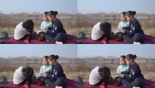 冬季在公园草坪上看书的三个女孩高清在线视频素材下载