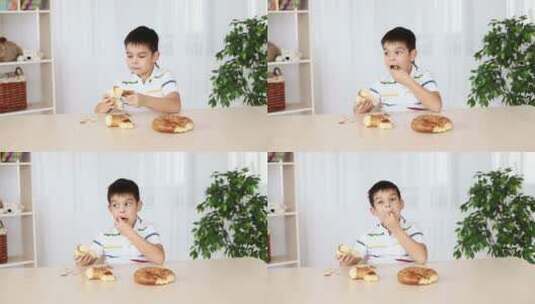 男孩坐在桌子旁吃面包高清在线视频素材下载