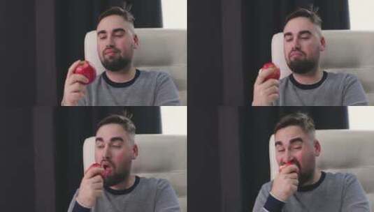 饥饿的男人坐在桌子前吃红苹果高清在线视频素材下载