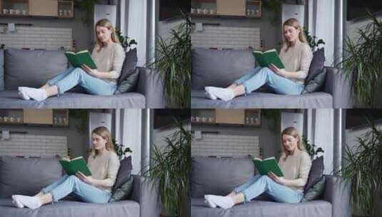 微笑的年轻女子坐在家里的沙发上看书。在舒高清在线视频素材下载