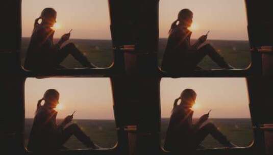 黄昏女人坐在窗边玩手机高清在线视频素材下载