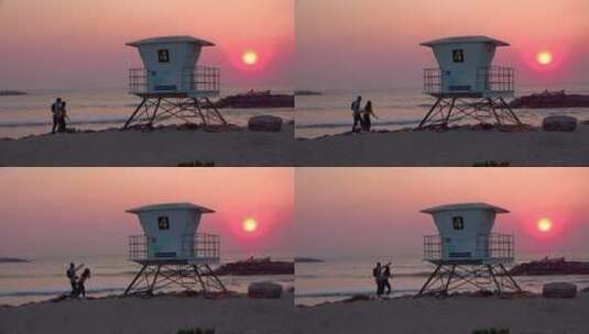 日落时两名游客走到海滩救生员站附近高清在线视频素材下载