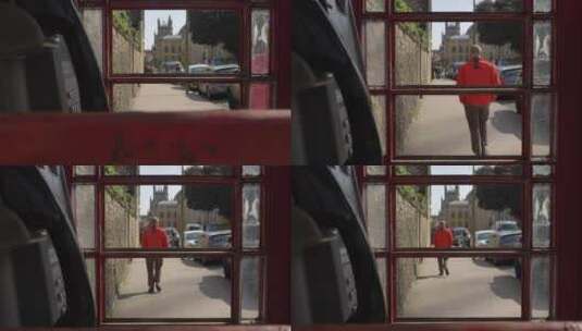 透过旧电话亭拍摄红衣服的男人走在街上高清在线视频素材下载