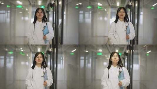 年轻女医生手持文件夹在走廊上行走高清在线视频素材下载
