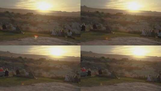 人们坐在山上草地的垫子上，看着温暖的日落高清在线视频素材下载