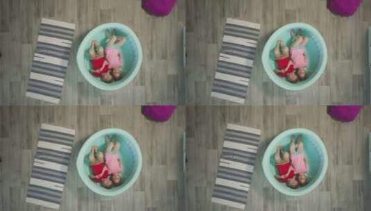 兄弟和姐妹躺在浅游泳池靠近地毯上地板高清在线视频素材下载