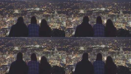 趴在山顶看城市夜景的三人高清在线视频素材下载