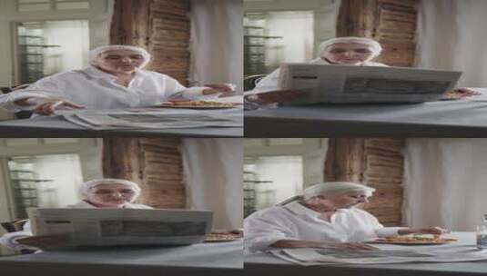 一位老妇人一边看报纸一边吃意大利面 竖屏高清在线视频素材下载