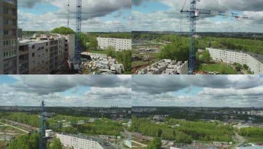 起重机在一个城市地区正在建设的建筑顶部，那里有树木和建筑高清在线视频素材下载