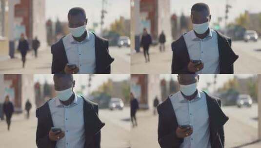 非洲人戴着口罩走在城市里玩手机高清在线视频素材下载