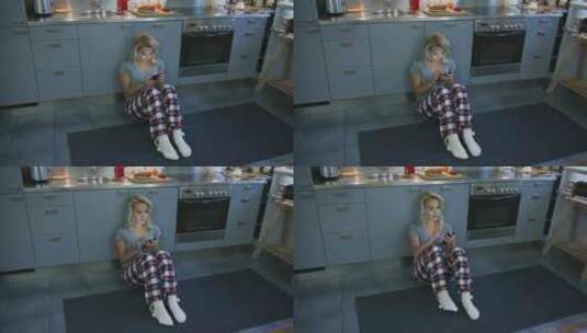 女孩坐在厨房地板上玩手机高清在线视频素材下载