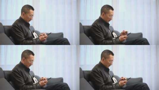 中年男子坐在客厅沙发上使用智能手机高清在线视频素材下载