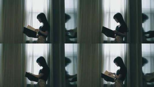 女孩在窗边看书的剪影视频素材高清在线视频素材下载