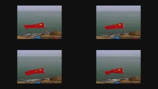 随风飘扬的国旗在海面的礁石上高清在线视频素材下载