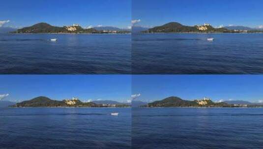 在意大利马焦雷湖平静的湖水中航行的小型摩托艇，后面有安吉拉城堡高清在线视频素材下载