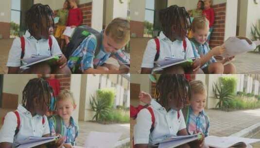 快乐的多样化男孩拿着书在学校前说话的视频高清在线视频素材下载