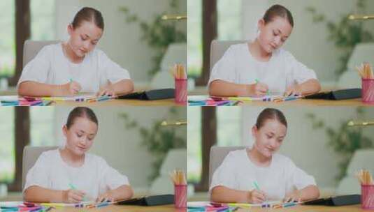 特写镜头专注于微笑的青少年女孩在办公桌上用绿色绒线笔在白纸上画画高清在线视频素材下载