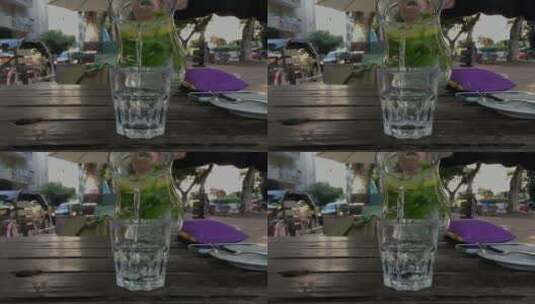 街头的木桌上向玻璃杯里倒柠檬水高清在线视频素材下载
