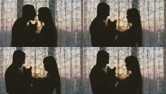 一对幸福的夫妇站在窗边亲吻的剪影高清在线视频素材下载
