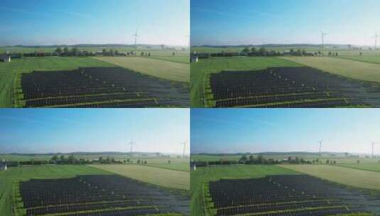 白天绿色田野中的太阳能电池板和风力涡轮机——无人机拍摄高清在线视频素材下载