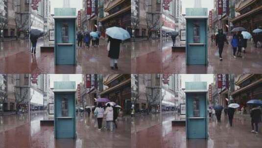 下雨天上海南京路电话亭旁行人撑伞走过高清在线视频素材下载