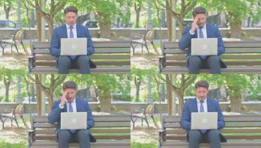 头痛的中年商人使用笔记本电脑，坐在户外高清在线视频素材下载