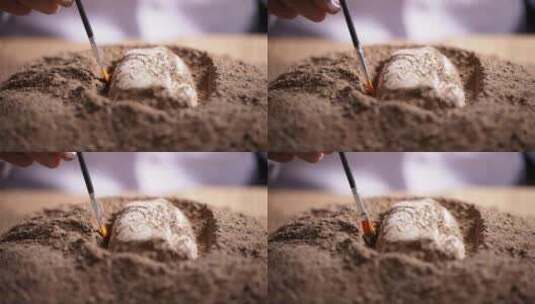 考古发掘人员用刷子轻轻扫去文物周边沙泥高清在线视频素材下载