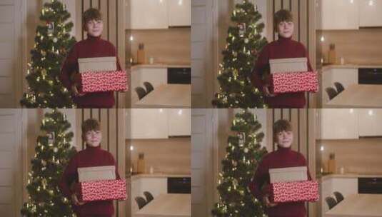 圣诞树前抱着礼盒的男孩高清在线视频素材下载
