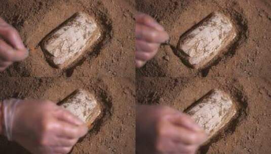 考古发掘人员用刷子轻轻扫去文物周边沙泥高清在线视频素材下载