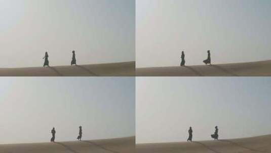 妇女在多风的沙漠中行走高清在线视频素材下载