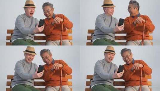 两位老年朋友坐在长椅上使用手机高清在线视频素材下载