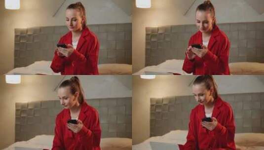 身穿红色夹克的年轻女子在床上从事智能手机高清在线视频素材下载