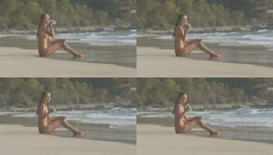 女孩在海滩上坐着喝水高清在线视频素材下载