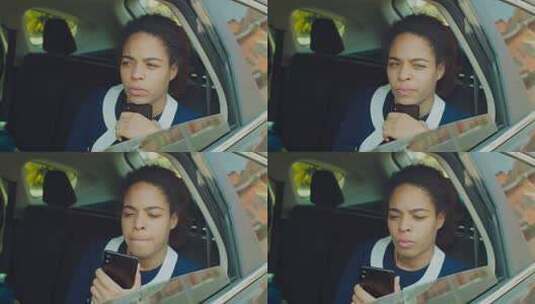 沉思的非裔美国女商人的肖像坐在汽车后座上，用智能手机支撑着下巴，看着车窗外，思考新的商业项目。高清在线视频素材下载