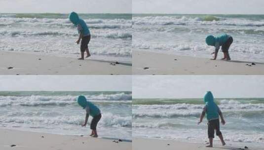 穿着背心的蹒跚学步的男孩正在海边玩沙子。高清在线视频素材下载