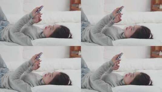 年轻女孩躺在床上玩手机刷视频高清在线视频素材下载