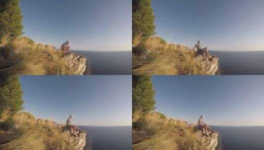 男人坐在海边岩石上看海景高清在线视频素材下载